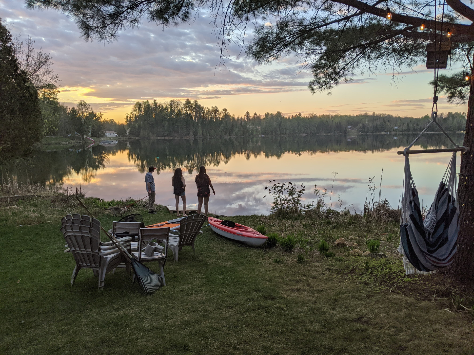 Sunset over a quiet lake with kayak and Muskoka chairs