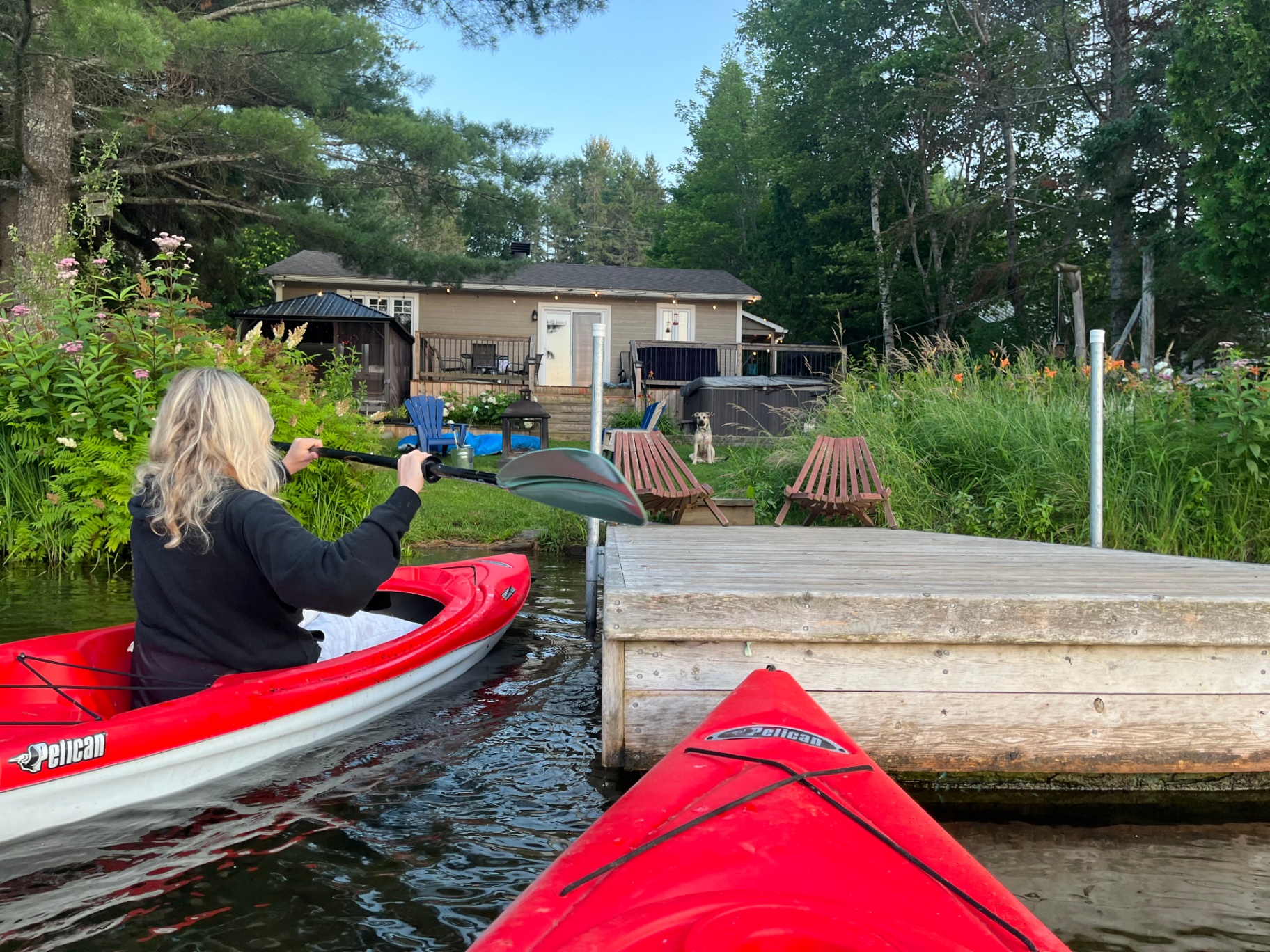 Sabine kayaking at sunset in front of a lakeside cottage