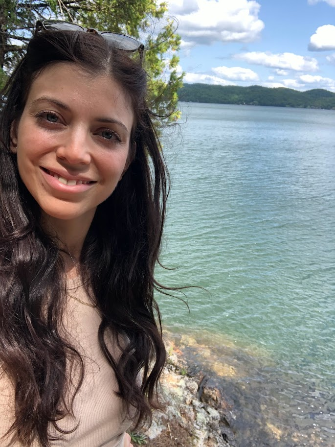 Ashley smiling by a sparkling blue Canadian lake