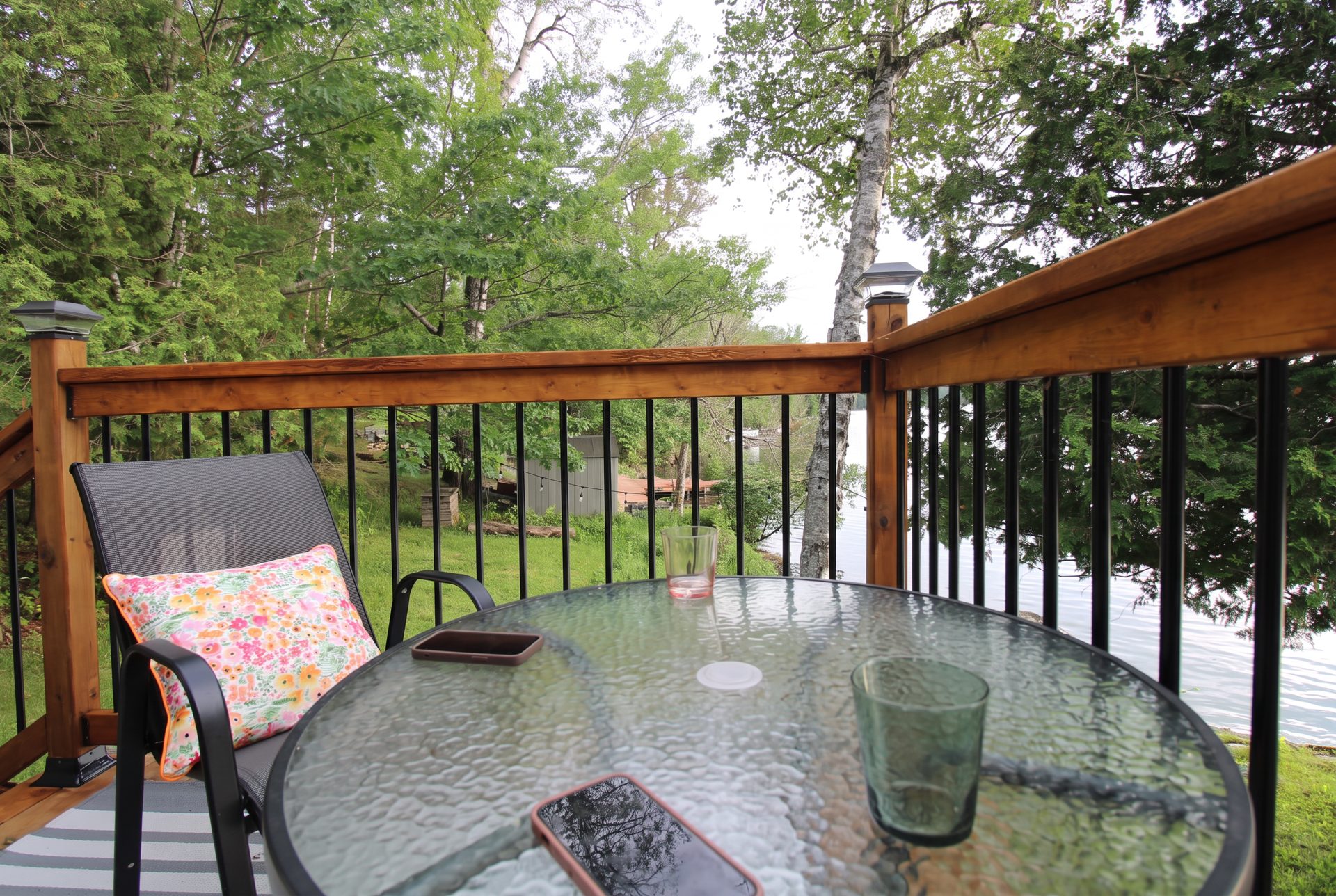 Cottage deck with glass table overlooking a calm lake