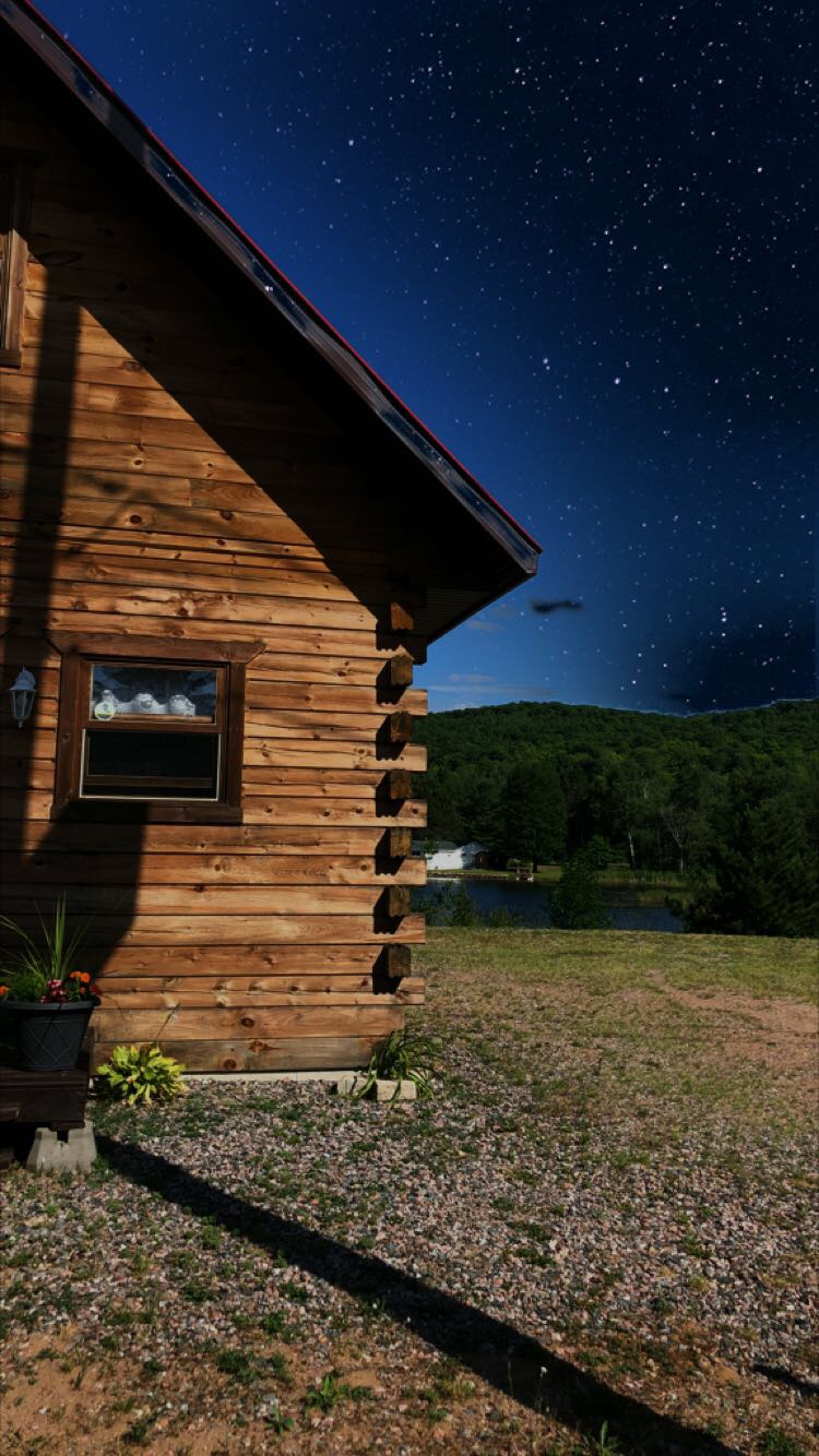 Log cabin under a starry night sky by the lake